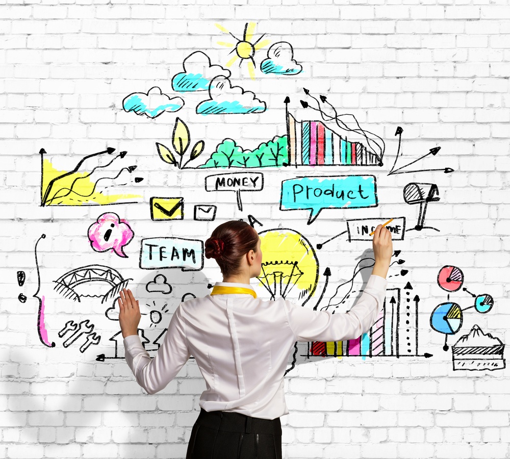 Businesswoman standing with back drawing conference planning ideas on wall.jpeg